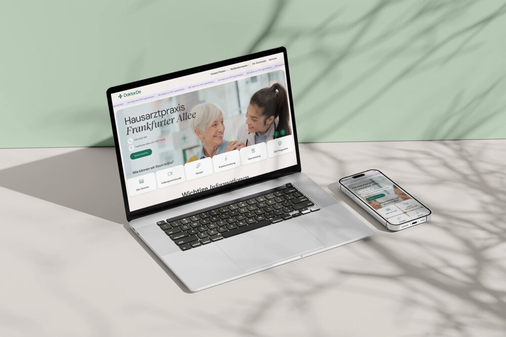 Laptop und Smartphone auf beigem Tisch, beide zeigen eine Website der Hausarztpraxis Frankfurter Allee mit Bild einer älteren Patientin und einer Ärztin, Hintergrund grün mit Baumzweigschatten